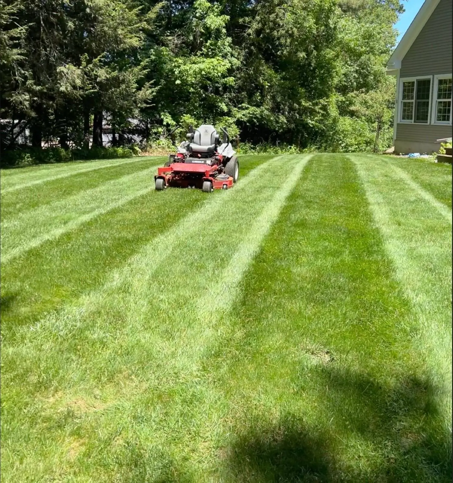 A zero-turn mower on a freshly striped lawn