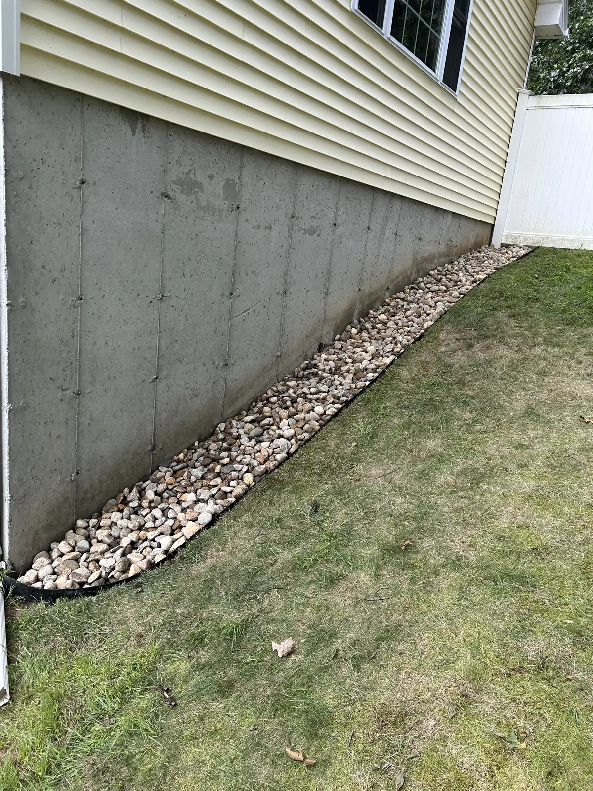 River rock along the foundation, edged against the lawn